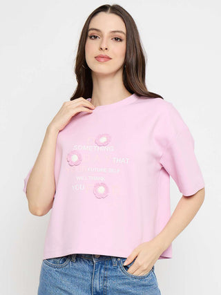 Woman wearing a pink t-shirt with floral designs on a white background