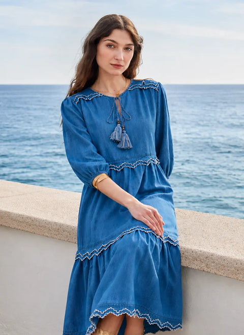 Woman in a blue denim dress with tassel details by the ocean